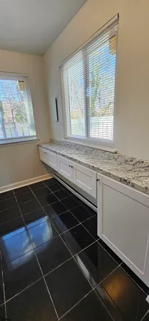 a kitchen with granite countertop a stove and white cabinets
