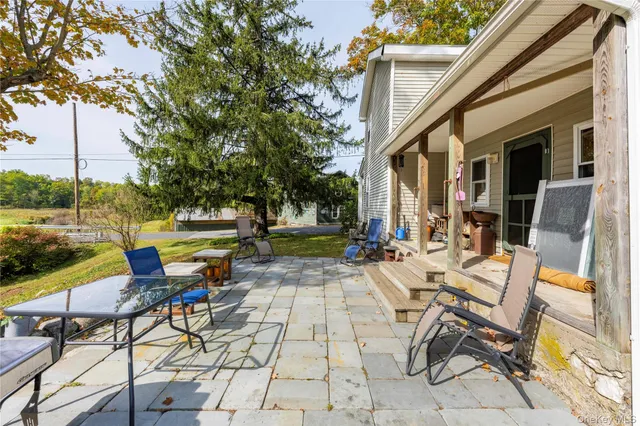 a view of a patio with table and chairs and floor to ceiling window