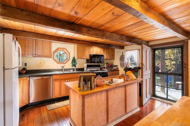 a view of a kitchen with stainless steel appliances granite countertop a refrigerator a stove and a wooden floor