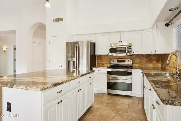 a kitchen with stainless steel appliances granite countertop a stove a sink and a refrigerator