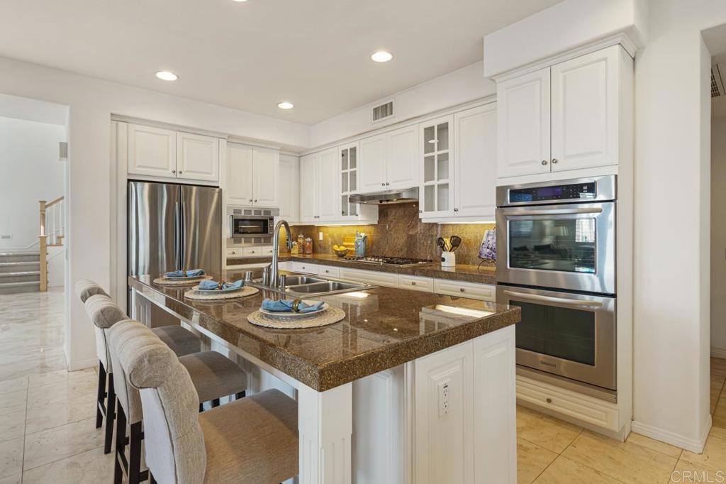 7357 Melodia Terrace Carlsbad, CA 92011 - Photo 19 of 60 a kitchen with kitchen island granite countertop a stove refrigerator and microwave