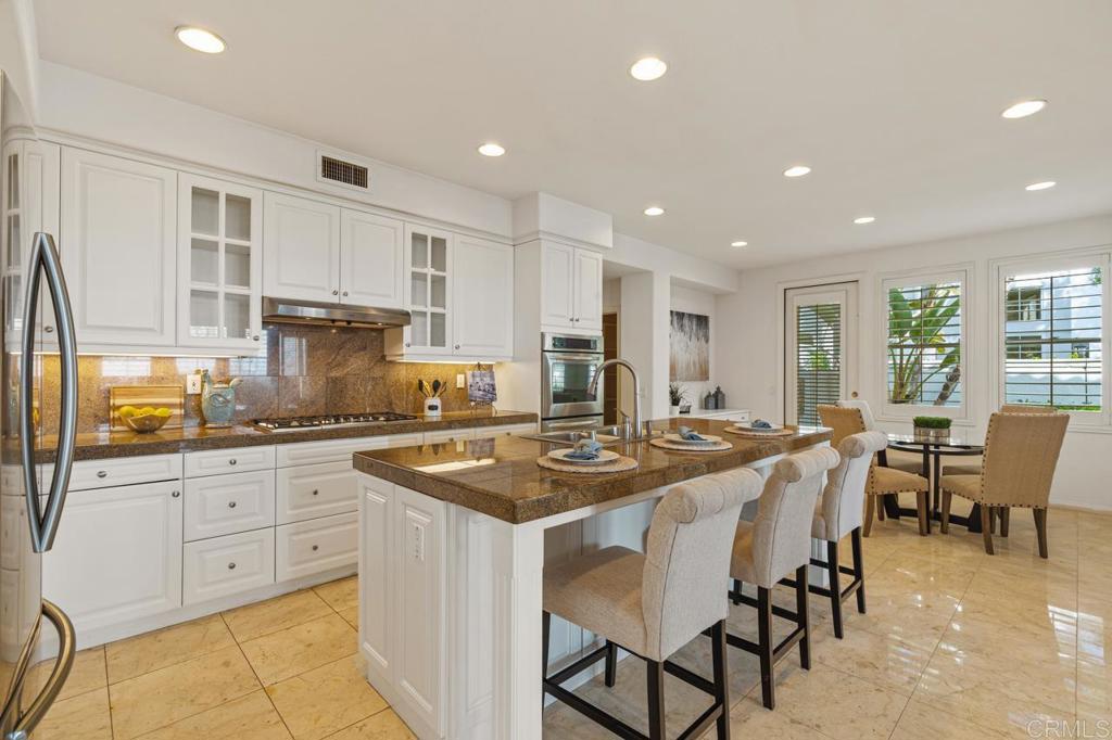 7357 Melodia Terrace Carlsbad, CA 92011 - Photo 22 of 60 a kitchen with stainless steel appliances granite countertop a stove and white cabinets
