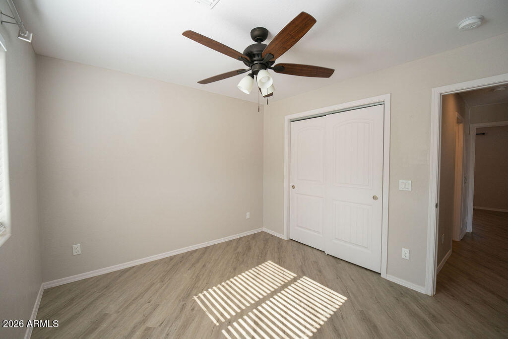 19643 East Rojo Road Florence, AZ 85132 - Photo 12 of 45 an empty room with wooden floor ceiling fan and a window