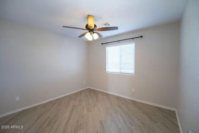 an empty room with wooden floor and a ceiling fan