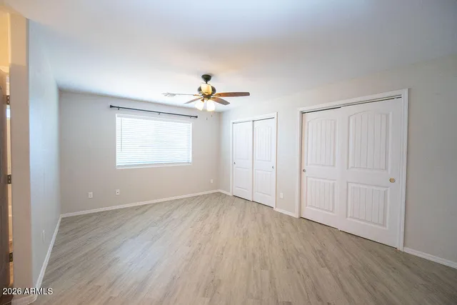 an empty room with wooden floor chandelier fan and windows