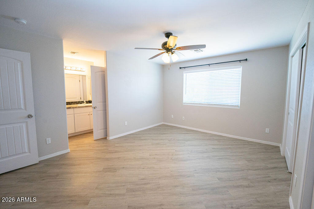19643 East Rojo Road Florence, AZ 85132 - Photo 32 of 45 an empty room with wooden floor chandelier fan and windows