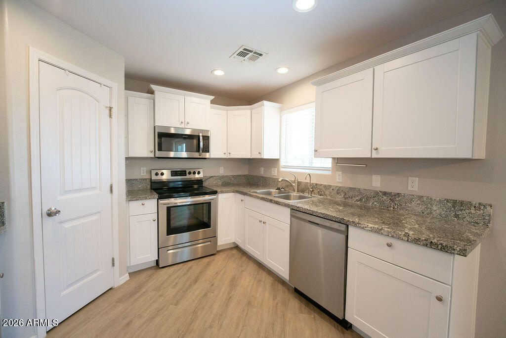 19643 East Rojo Road Florence, AZ 85132 - Photo 42 of 45 a kitchen with granite countertop white cabinets and stainless steel appliances