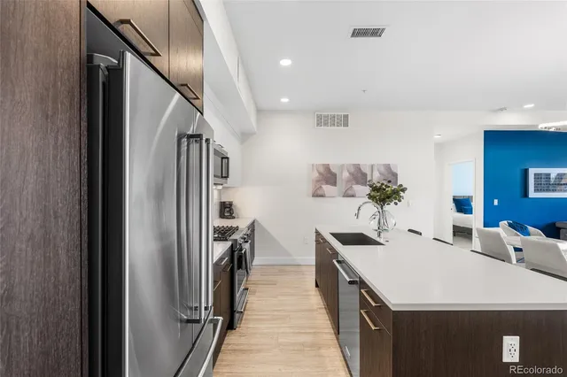 a dining room with stainless steel appliances kitchen island a table chairs and refrigerator