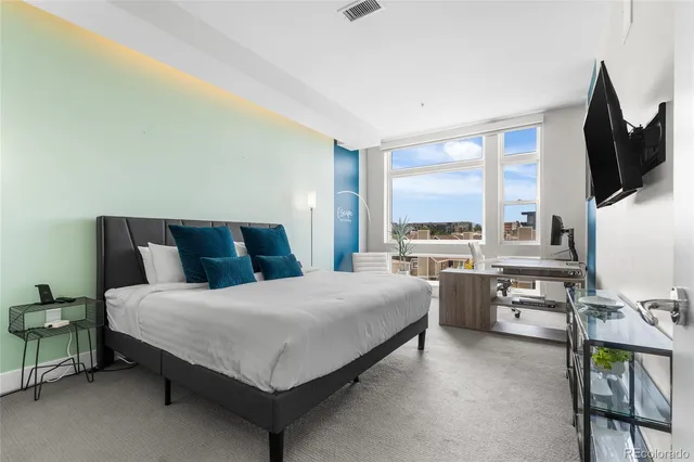 a bedroom with a large bed and a flat tv screen on dresser