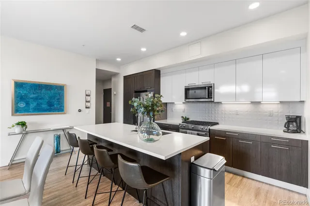 a kitchen with stainless steel appliances granite countertop a sink a stove a microwave a dining table and chairs