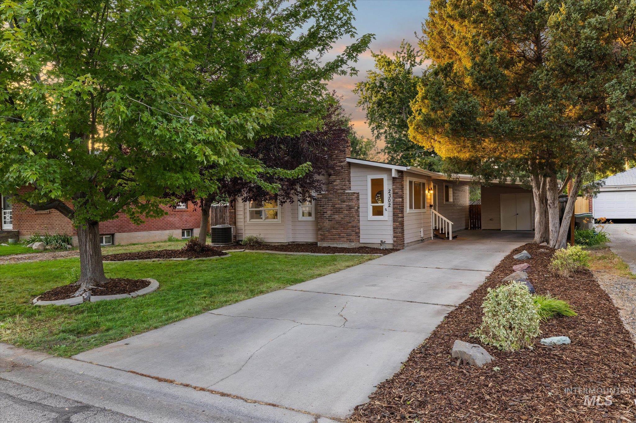 Ranch-style exterior with light-colored siding, a stone-clad chimney, and a covered entryway