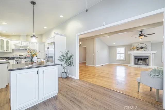 a kitchen with stainless steel appliances granite countertop a refrigerator a sink dishwasher a stove and white cabinets with wooden floor