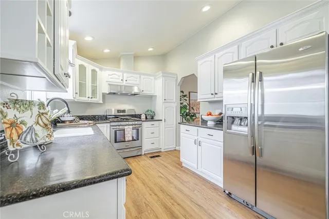a kitchen with stainless steel appliances granite countertop a refrigerator a stove and a sink