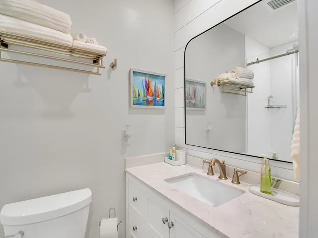 a bathroom with a sink vanity mirror and toilet