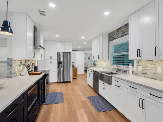 a large kitchen with stainless steel appliances sink a stove and cabinets