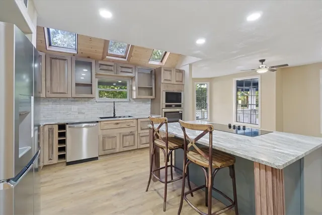 a kitchen with stainless steel appliances kitchen island granite countertop a stove a sink and a refrigerator