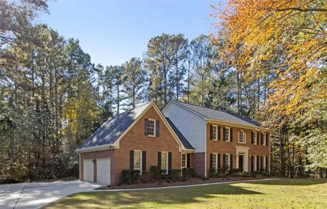 a view of a house with a yard and large trees