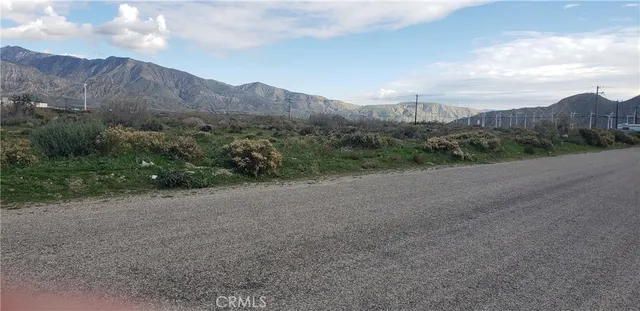 a view of a dry field with mountains in the background