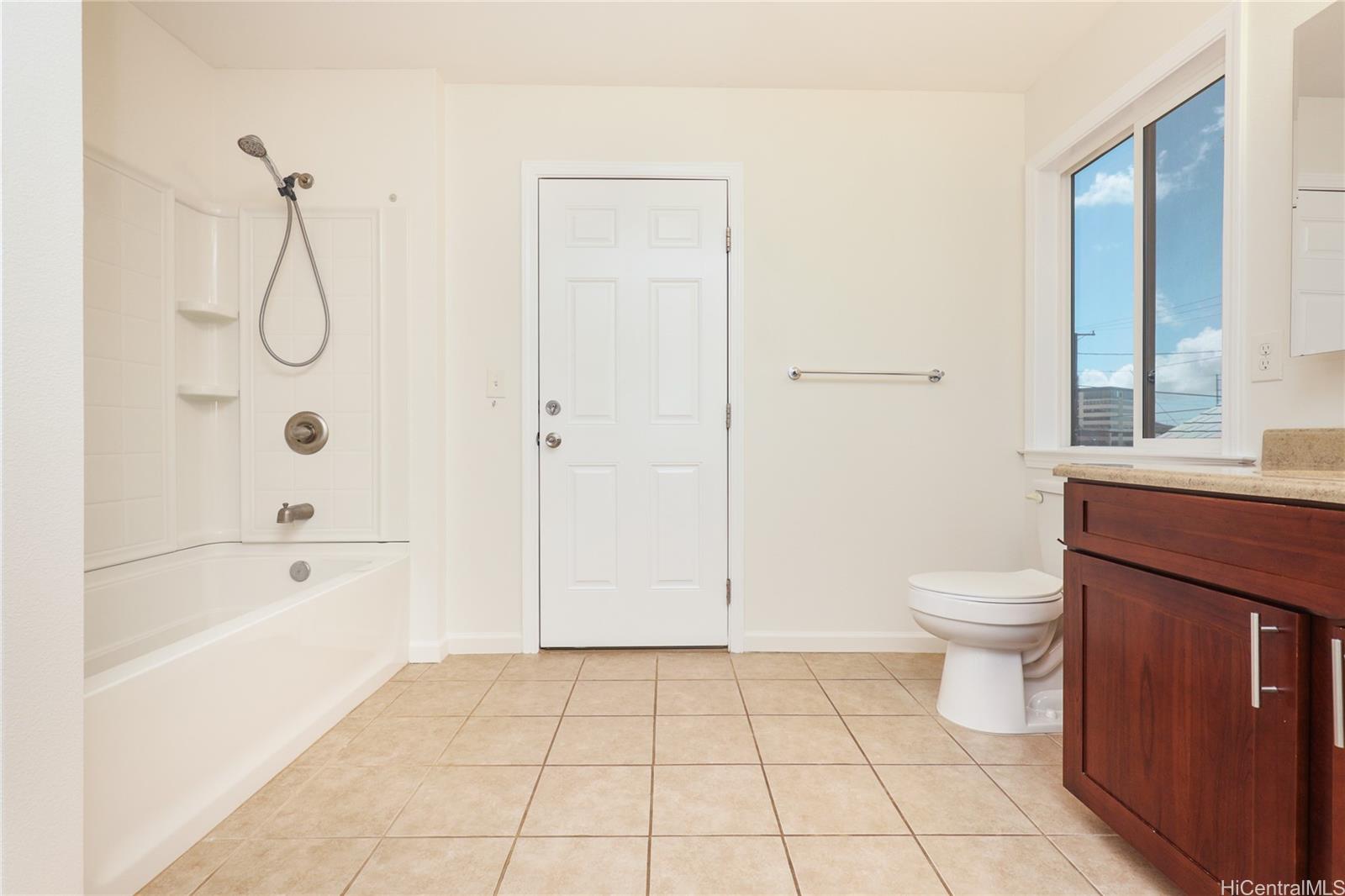 99-036 Moanalua Road, Unit A1 Aiea, HI 96701 - Photo 9 of 18 a bathroom with a granite countertop toilet a sink and a bathtub