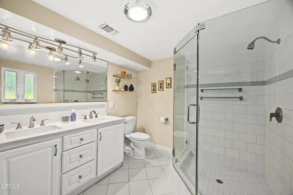a spacious bathroom with a double vanity sink toilet mirror and shower