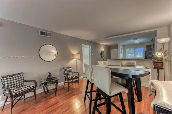 a kitchen with stainless steel appliances granite countertop a stove top oven a sink dishwasher a dining table and chairs with wooden floor