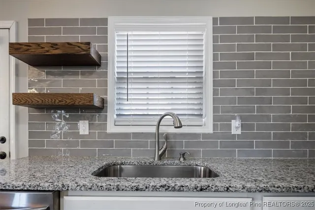 a bathroom with a granite countertop a sink and a window