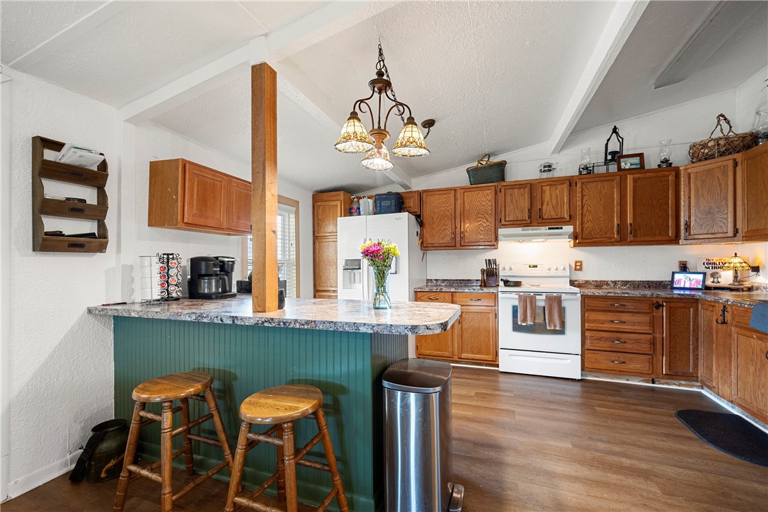 7017 County Road 2253 Odem, TX 78370 - Photo 36 of 40 a kitchen with stainless steel appliances granite countertop a stove top oven a kitchen island and chairs with wooden floor