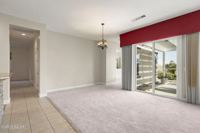 a view of a livingroom with a chandelier fan and windows