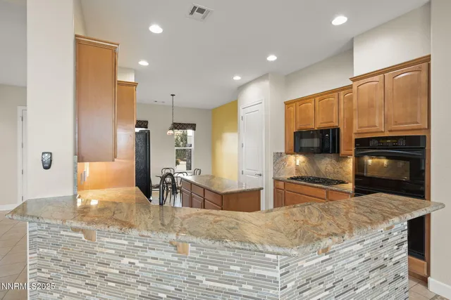 a kitchen with stainless steel appliances kitchen island granite countertop a refrigerator oven a sink with island and chairs