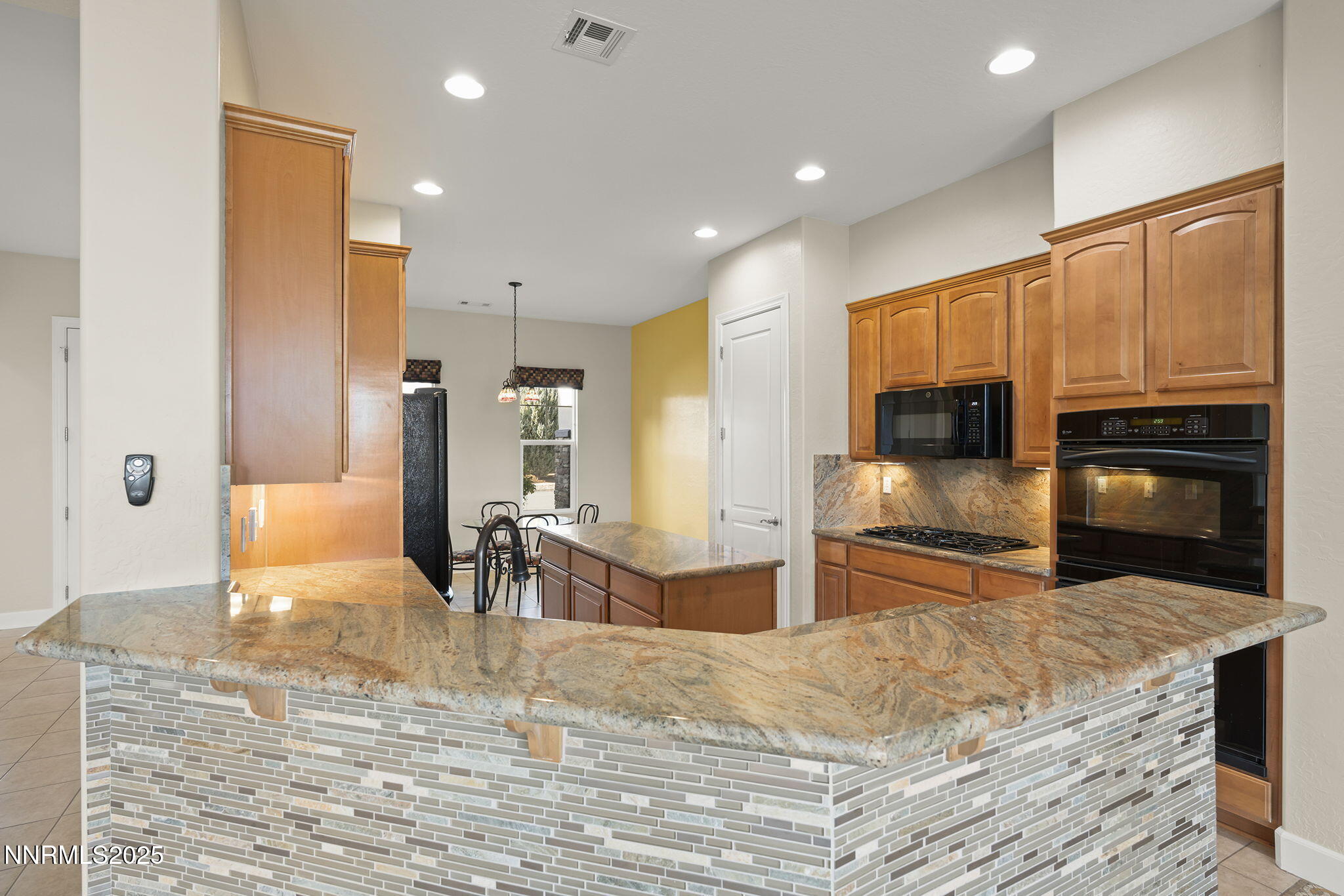 9190 Quilberry Way Reno, NV 89523 - Photo 9 of 39 a kitchen with stainless steel appliances kitchen island granite countertop a refrigerator oven a sink with island and chairs