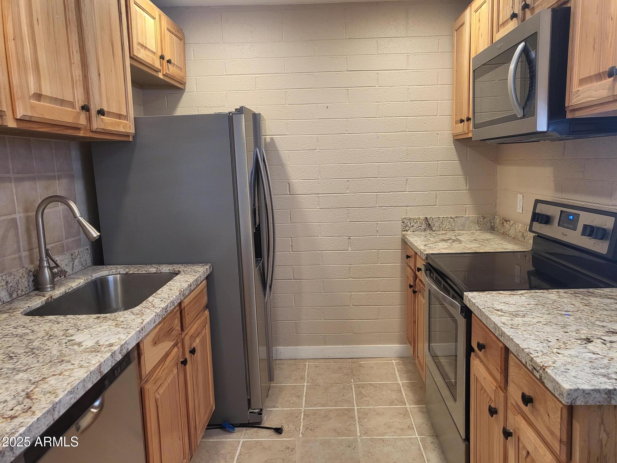 815 North Hayden Road, Unit A204 Scottsdale, AZ 85257 - Photo 9 of 27 a kitchen with stainless steel appliances granite countertop a sink stove and refrigerator