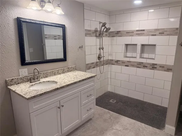 a bathroom with a granite countertop sink a mirror and a shower