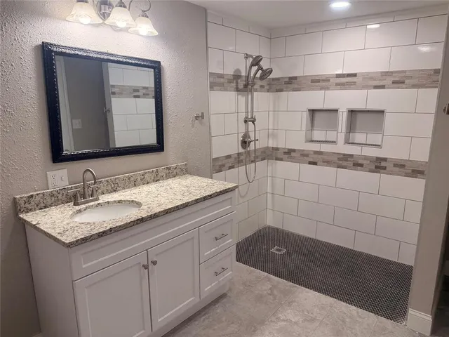 a bathroom with a granite countertop sink a mirror and a shower