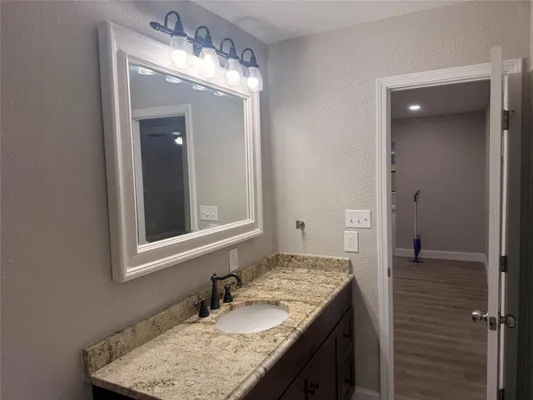 a bathroom with a granite countertop sink and a mirror