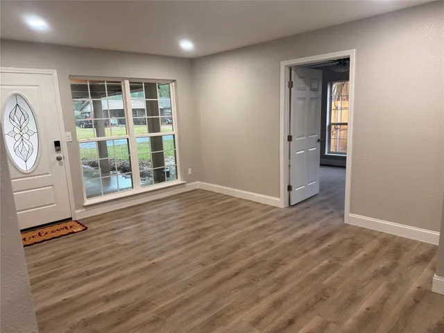 an empty room with wooden floor and windows