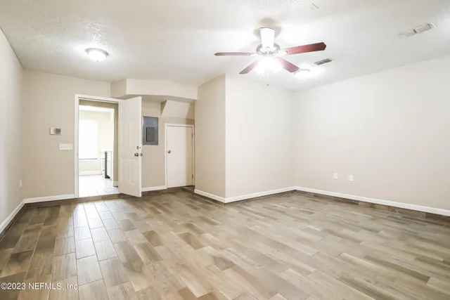 a view of an empty room with wooden floor and a window