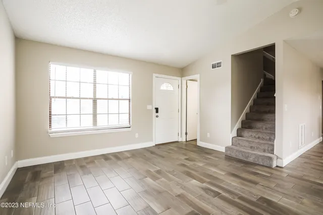 a view of a livingroom with a chandelier fan and windows