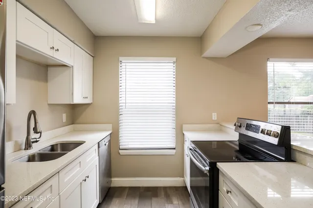 an empty room with a chandelier fan and windows