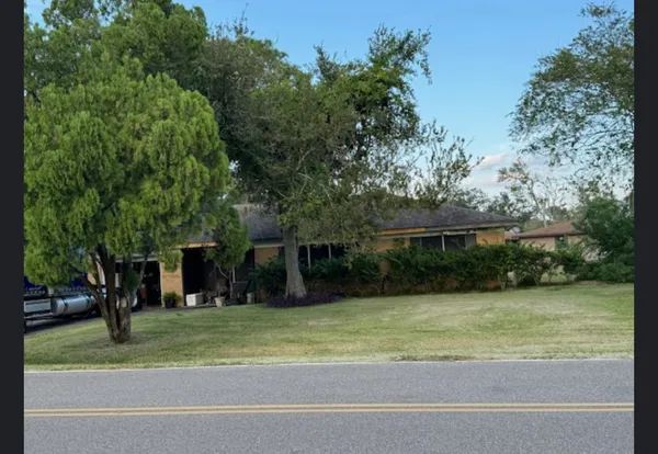 a view of a house with a yard and large trees
