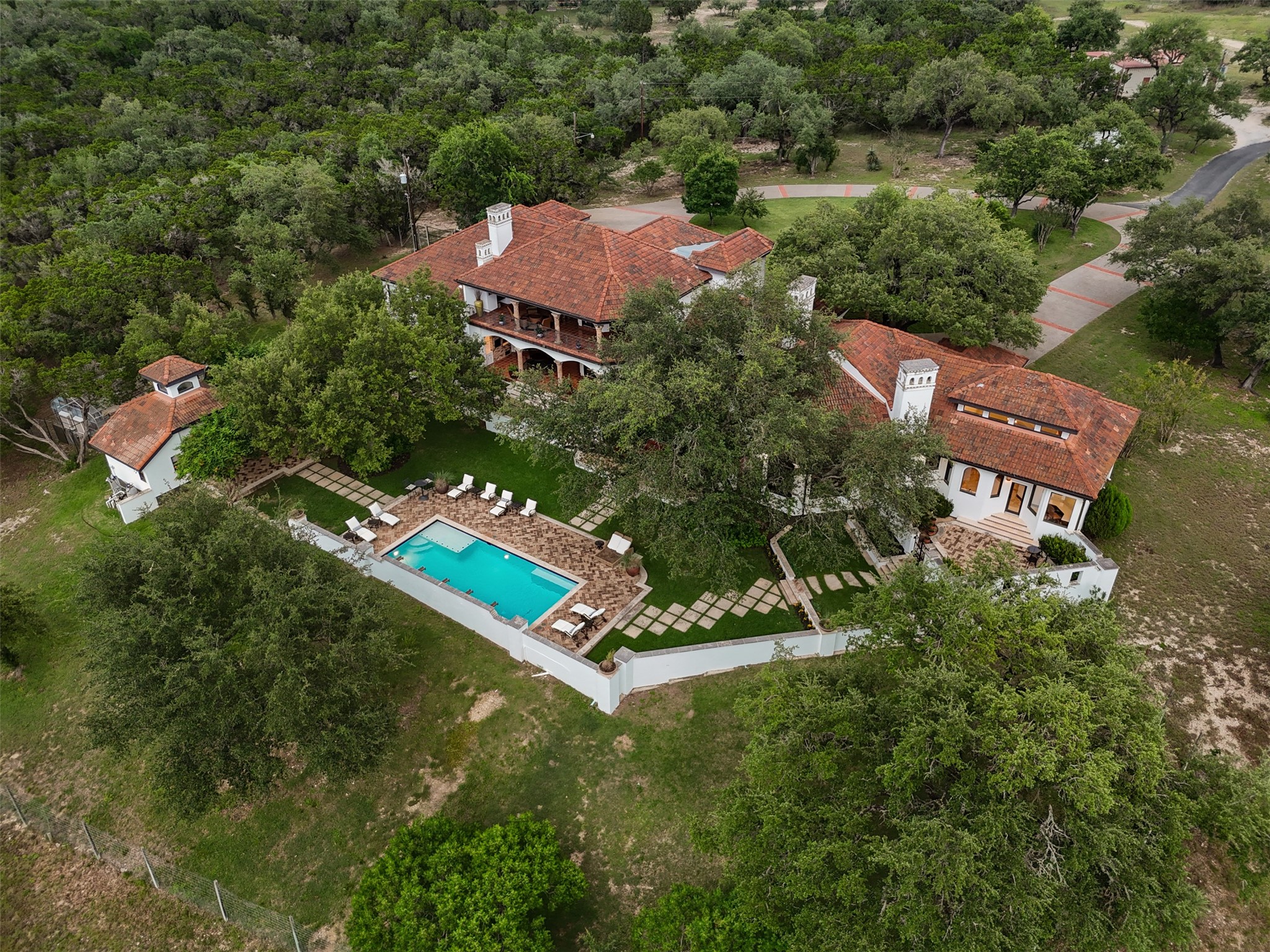 34000 Smithson Valley Road Bulverde, TX 78163 - Photo 49 of 50 From above, the estate reveals its resort-style outdoor living spaces, sparkling pool, and timeless Mediterranean architecture tucked beneath a canopy of heritage live oaks. The thoughtfully designed grounds create a private sanctuary surrounded by breathtaking Hill Country scenery.