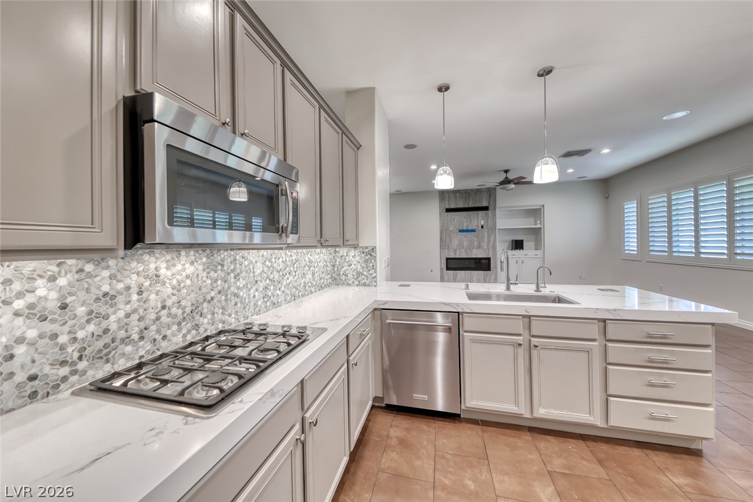 2122 Mooreview Street Henderson, NV 89012 - Photo 11 of 44 A well-appointed kitchen features a gas cooktop and stylish backsplash, overlooking an inviting living area.