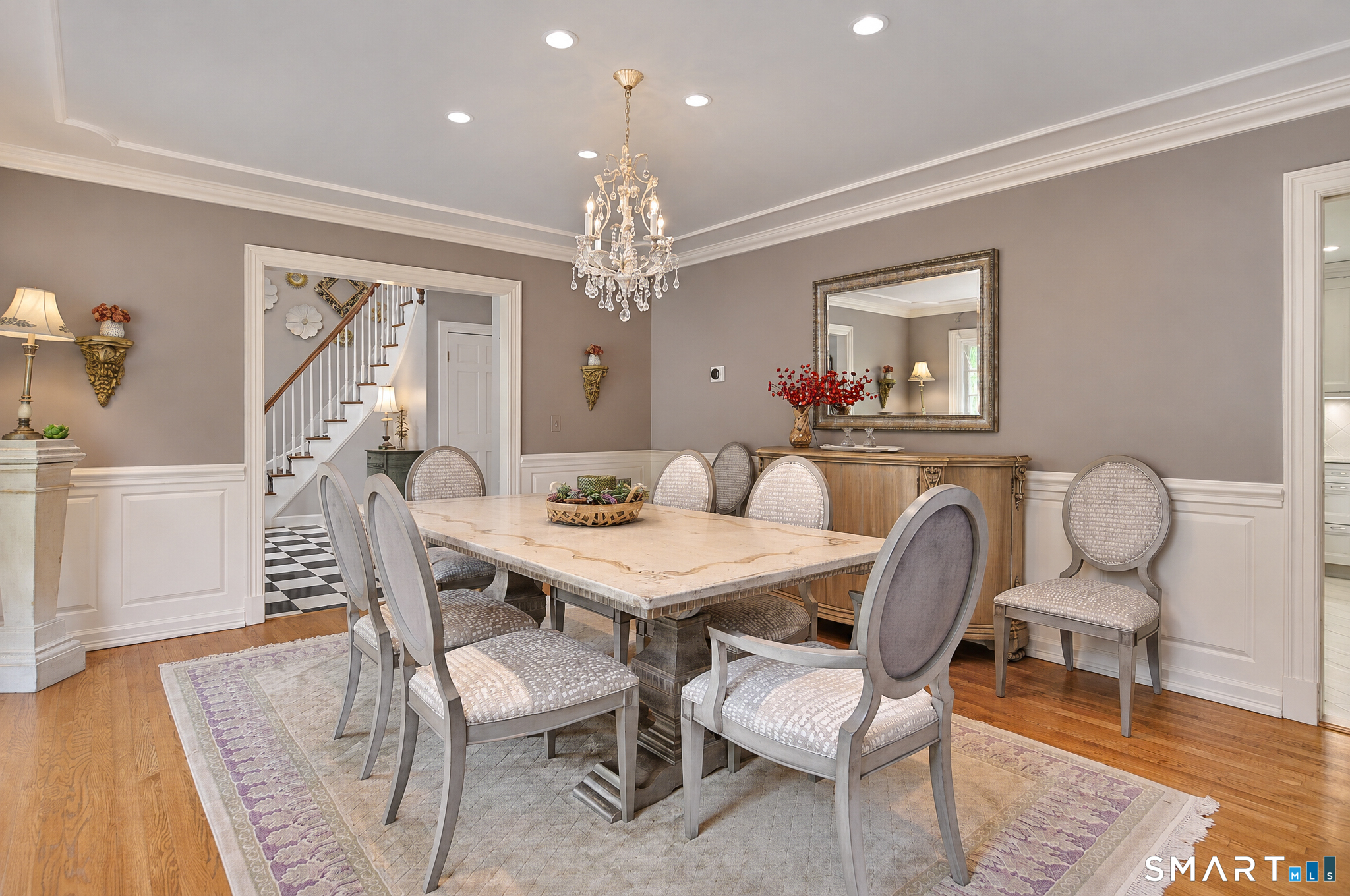 Formal dining room with hardwood flooring, detailed millwork, crown molding and elegant chandelier.