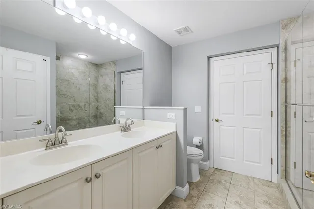 a bathroom with a double vanity sink mirror and toilet