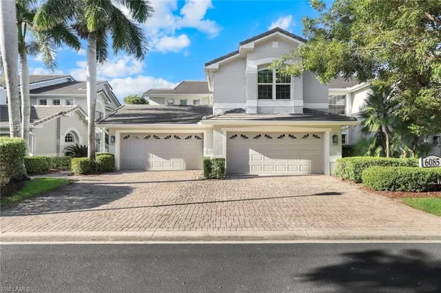 front view of house with a yard and palm trees