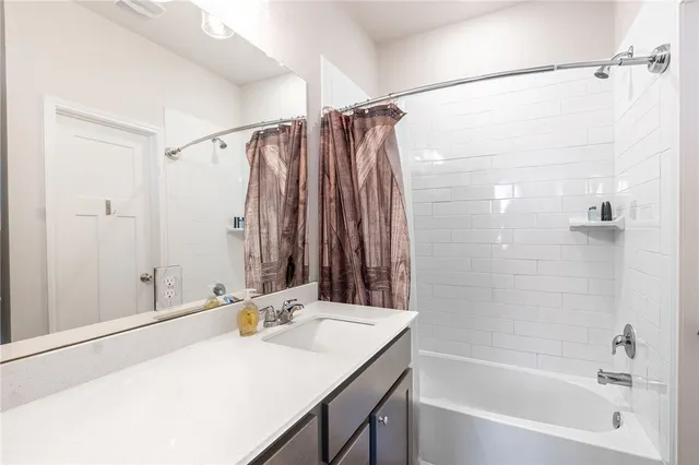 a bathroom with a sink vanity granite tub shower and a mirror