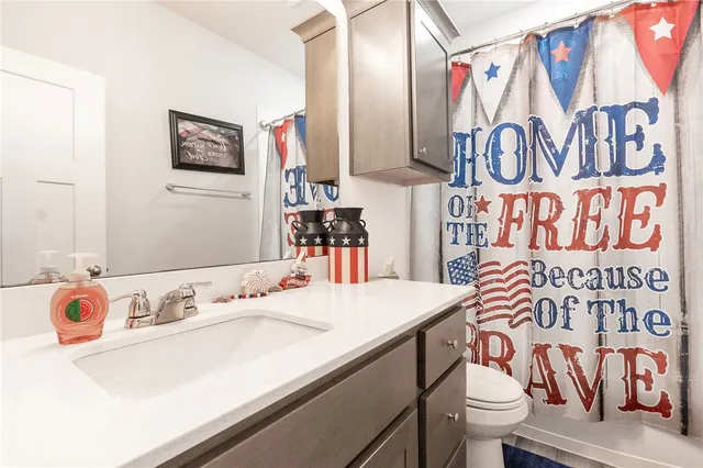 a bathroom with a sink a toilet and shower curtain