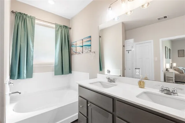 a bathroom with a tub sink and mirror