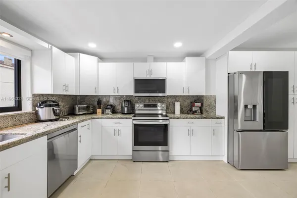 a kitchen with granite countertop white cabinets and stainless steel appliances