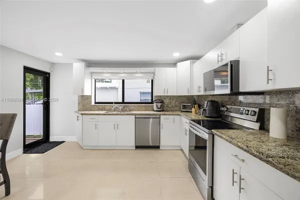 a kitchen with granite countertop white cabinets and stainless steel appliances