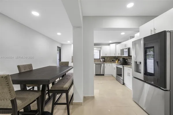 a kitchen with stainless steel appliances kitchen island granite countertop a refrigerator a stove a sink a dining table and chairs